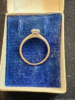 Ring in box showing band profile and prong setting