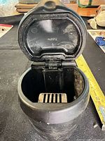 Ashtray open showing hinged lid, interior and metal grate