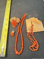 Necklace, broken strand, brooch, small cluster, tape for scale