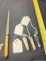 Overview of letter opener and three pocket knives on measuring tape