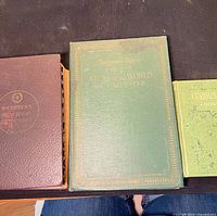 Front covers of all three books side by side: Webster's New Ideal Dictionary, 1925 Literary Digest Atlas, Curious Facts