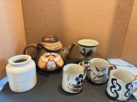 Group view of teapot, three mugs, jar and goblet