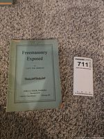 Front cover of Freemasonry Exposed book next to lot card