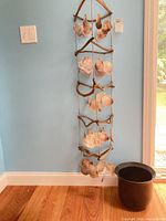 Full view of hanging shell and driftwood wind chime with ceramic pot on floor