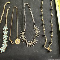 Four jewellery pieces laid out on black background with ruler for scale