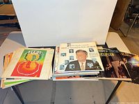 Wide shot of two stacks of LPs on table showing quantity and some titles
