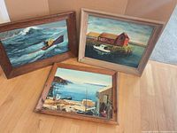 All three framed paintings side by side on floor