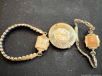 Overview of three gold-tone watches: Timex with stretch band, unmarked pendant watch, Fairfax with link bracelet