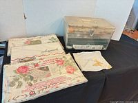 Overview of three packaged sheets, handkerchief, and sewing box