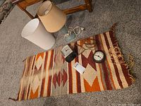 Group shot of lamp with shades, both clocks, woven runner