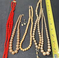 Overview of all necklaces and earrings with measuring tape for scale
