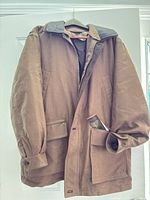 Full view of brown waxed cotton canvas coat on hanger