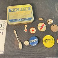 Group shot of all items including tin, buttons, pins, medal and spoon