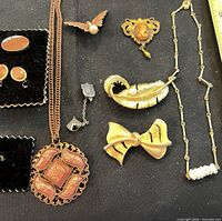 Group shot of all nine gold-tone jewelry pieces on black background