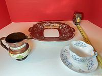 Overall lot showing cup, saucer, creamer, plate with tape for scale