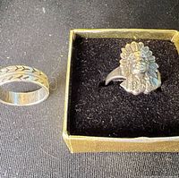 Both rings side by side; chief ring in box, band ring showing engraved pattern