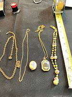 All four jewellery pieces laid beside ruler for scale