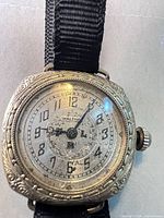 Front view of Waltham wristwatch showing dial, bezel engravings, hands and ribbon strap