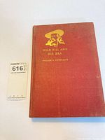 Front cover of red cloth hardback with gilt image and title, MaxSold lot card visible