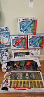 Wide photo showing entire lot including 3 aircrafts, electronic keyboard, toy cars, skateboards, and robot.