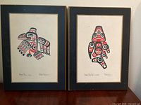 Two framed Bill Reid prints showing Haida Dogfish and Haida Raven designs mounted on plaques.