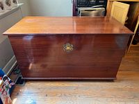Front view of a rectangular wooden chest with polished surface and keyhole decoration.