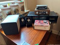 Photo showing vintage Remington electric shaver in box, Logitech and Dell computer speakers, JVC cassette deck, and two car stereos stacked on furniture.