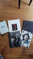 All seven fashion coffee table books arranged loosely on the floor showing various front covers and slipcovers including Prada Catwalk and Jeremy Scott.