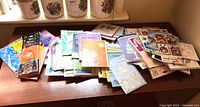 Full view of assorted greeting cards and wrapped tissue paper spread out on a wooden surface.