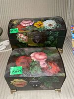 Two hand-painted wooden boxes on fabric surface, showing floral design on curved lids and brass feet, with green size stickers visible