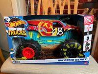 Front view of the Hot Wheels HW Demo Derby monster truck in original box showing colorful graphics and large tires.