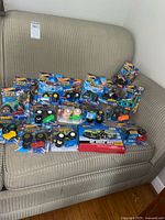 Image showing full assortment of Hot Wheels Monster Trucks in original packaging on sofa.