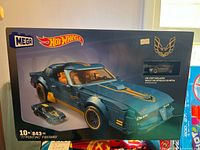 Front of the original Mega Hot Wheels box showing the assembled 1977 Pontiac Firebird model with gold decals and included die-cast miniature car.