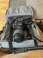 Minolta X-700 camera inside gray and black soft camera bag on wooden floor surface