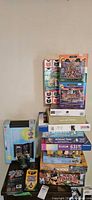 Photo showing stacked unopened boxed puzzles and games including 1000-piece puzzles, zombie domino game, and multimedia artist set.