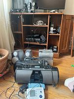 Front and overall view of lot items including docking system with speakers, Panasonic radio cassette player, Sanyo CD player system with speakers, and Vtech cordless phones with bases