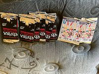 Three opened packs of Elvira trading cards and three unopened Sailor Moon packs on fabric background.