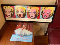Full view of both Marilyn Monroe prints, including the framed Warhol style silkscreen print on top and Marilyn Monroe tin sheet print below.