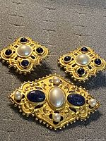 front view of brooch and earrings showing design and stones