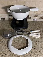 complete fondue set laid out: pot on stand, burner, splash guard, five forks