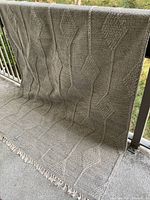 Full view of rug draped over railing showing size, overall pattern and fringe