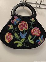 Front view of black beaded handbag showing floral and butterfly beadwork