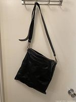 Full view of M0851 black leather bag hanging by strap