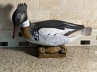 Profile view of carved merganser decoy on stand