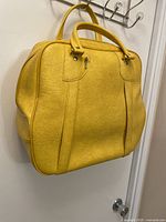 Front view of yellow leather travel bag showing handles and textured leather