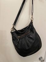 Front view showing bag shape, exterior zipper pocket, strap and hardware