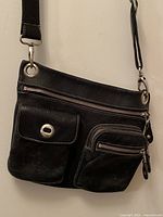 Front view showing pockets, strap, hardware