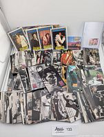 Wide shot showing a large assortment of Elvis Presley trading cards, vintage cards in black and white and color, note pads and a small stamp sheet.
