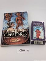 Photo showing the front cover of the Devilish Greetings vintage devil postcards book and the 1985 Prediction Tarot Deck box