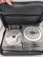 Black binder CD holder with two pages of CDs visible, showing various album discs inside plastic sleeves.